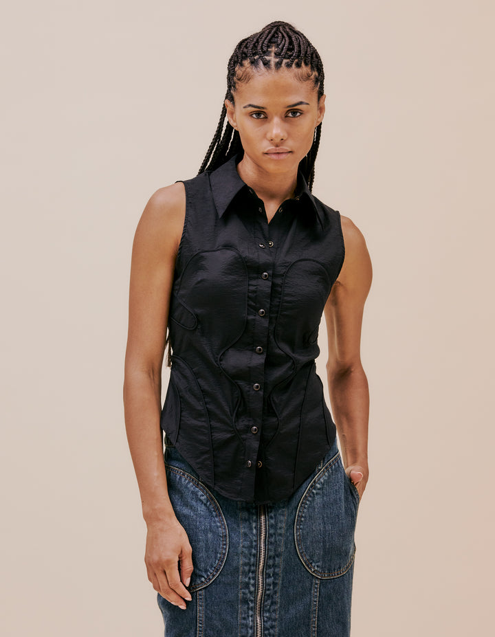This slim fitting sleeveless button down is crafted in a novel synthetic stretch Japanese nylon shirting with curvinlear piping details throughout evocative of western shirting details. Complete with a shirt collar and pearl snap closures. Model wear size small. Made in China. 93% POLYAMID 7% POLYURETHANE