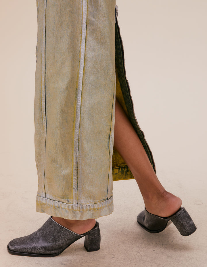 Mid-length skirt in garment washed denim with full-length exposed center zipper down the front and back. Indigo denim is enzyme washed, then overdyed in citrine, then entirely foiled in silver. Slim fit and low rise with rounded pockets at the hip and an exaggerated yoke in the back. Finished with an extended waistband and nickel hardware. Model wears size S. Made in USA. 100% cotton.