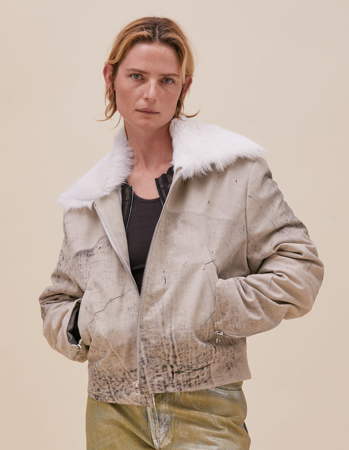 This jacket is crafted in distressed deadstock cow leather hand selected in Portugal. Cropped and boxy in fit, the garment is complete with a goat fur poet collar, tailored sleeves, welt pockets and zippers at center front and sleeve hem. Fully lined with a slight fill. Models wear size M. Made in Portugal. 100% leather, lining 100% polyester.