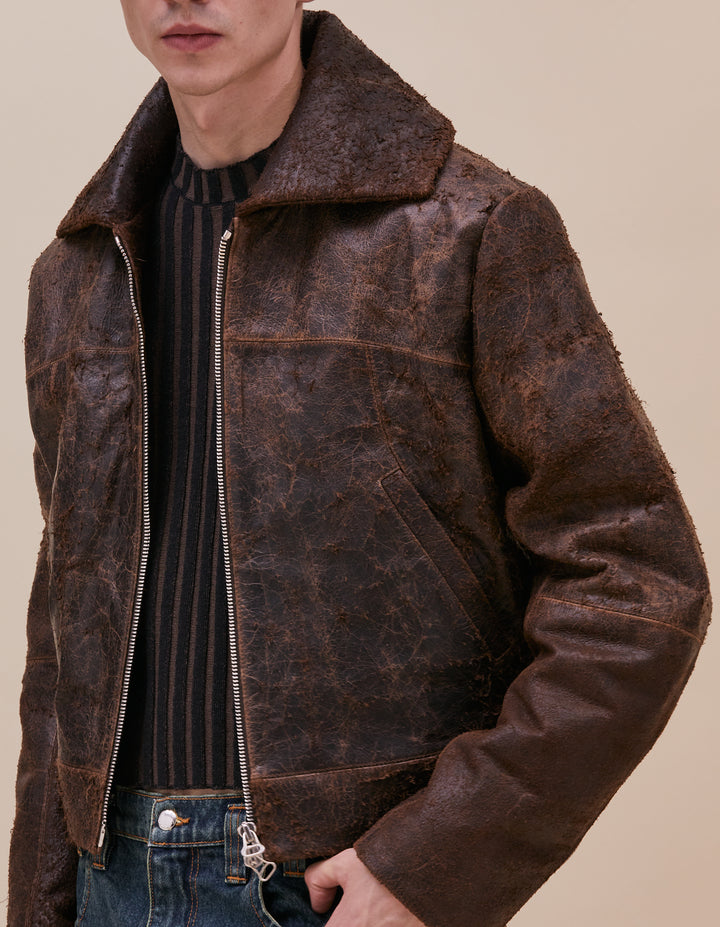 This jacket is crafted in distressed deadstock cow leather hand selected in Portugal. Cropped and boxy in fit, the garment is complete with a poet collar, tailored sleeves, welt pockets and zippers at center front and sleeve hem. Fully lined with a slight fill. Models wear size M. Made in Portugal. 100% leather, lining 100% polyester.