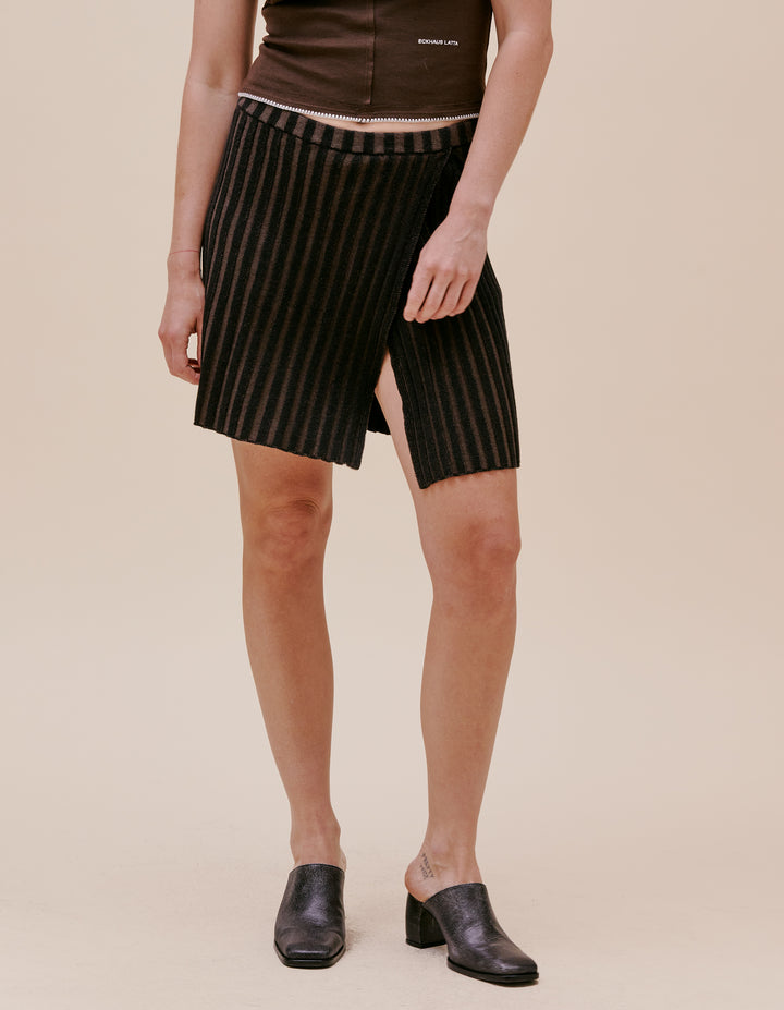 This mini skirt is knit with a plated rib in a dry linen/cotton blend. Overlapping slit at thigh and elastic waist band. Model wears size small. Made in China. 55% linen, 45% cotton.